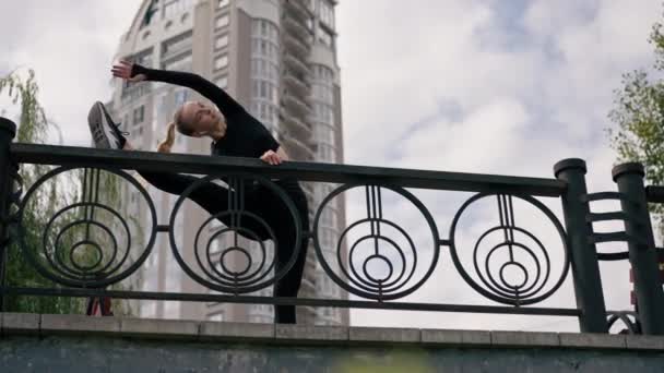 女の子アスリートは川を見下ろす銀行の足の柔軟性のために朝ストレッチ — ストック動画