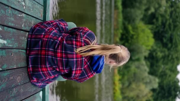 Pionowe Wideo Widok Tyłu Dziewczyna Siedzi Brzegu Rzeki Lub Jeziora — Wideo stockowe