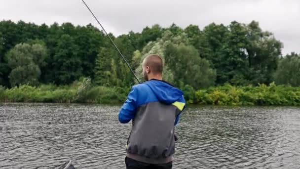 渔夫拿着钓竿或纺鱼竿和专业工具站在河岸上 把鱼拖出湖中钓鱼 — 图库视频影像