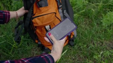 Doğanın arka planında bir turist sırt çantasının yakın çekimi. Elinde akıllı bir telefon ve harita var. Profesyonel ekipman.
