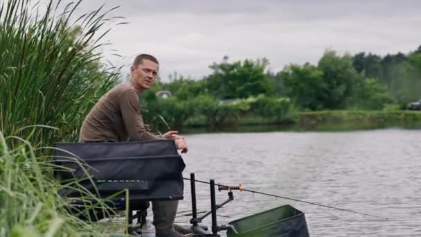 Balıkçı Elinde Olta Dönen Olta Profesyonel Aletlerle Nehir Kıyısında Oturur — Stok video
