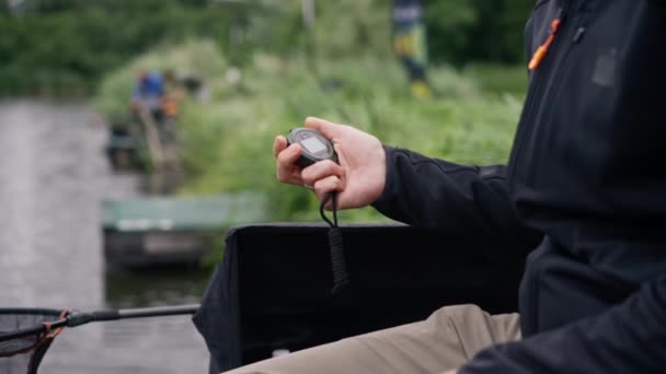 Χέρι Ενός Ψαρά Κρατά Ένα Χρονόμετρο Ένα Σημύδα Ποταμού Κατά — Αρχείο Βίντεο