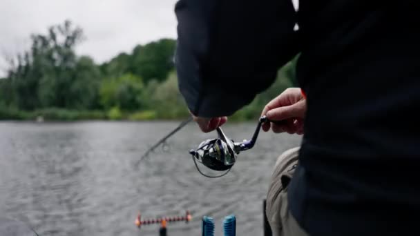 Close Fisherman Med Fiskestang Eller Spinding Professionelt Værktøj Sidder Flodbredden – Stock-video