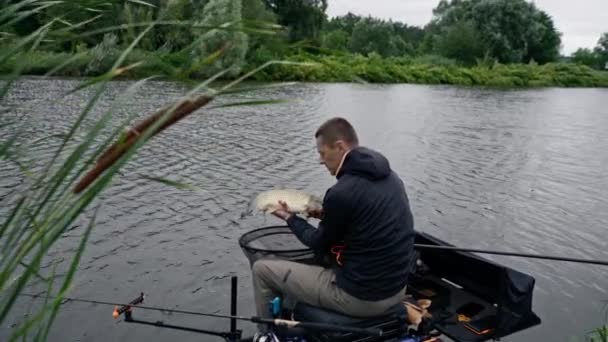 貯水池で釣りの川岸でカープ魚を飼っているプロの漁師の肖像画 — ストック動画