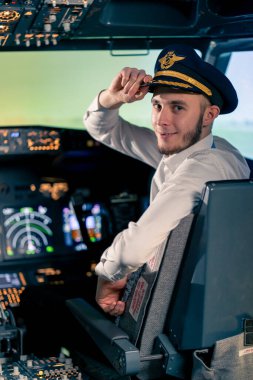 Üniformalı gülümseyen yüzbaşının portresi uçuş simülatörü kokpitinde uçuş hazırlıyor.