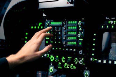 Pilot kaptanın yakın plan eli, uçuş simülatörünün motorunu çalıştırmak için kontrol panelindeki düğmelere basar.