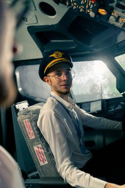 Uçağın kokpitindeki genç pilotlar uçuş sırasında hava taşımacılığını kontrol ederler. Uzak mesafe simülatörünün penceresinden güneş parlar.