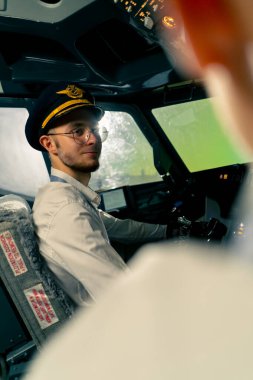 Uçağın kokpitindeki genç pilotlar uçuş sırasında hava taşımacılığını kontrol ederler. Uzak mesafe simülatörünün penceresinden güneş parlar.