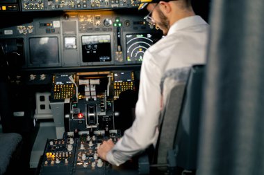 Pilot, yolcu gemisini kalkışa hazırlamak için düğmelere basarak uçağın elektronik aletlerini kontrol ediyor.