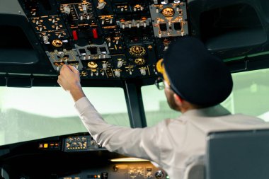 Pilot, yolcu gemisini kalkışa hazırlamak için düğmelere basarak uçağın elektronik aletlerini kontrol ediyor.