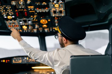 Pilot, yolcu gemisini kalkışa hazırlamak için düğmelere basarak uçağın elektronik aletlerini kontrol ediyor.