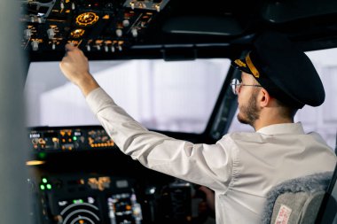 Pilot, yolcu gemisini kalkışa hazırlamak için düğmelere basarak uçağın elektronik aletlerini kontrol ediyor.