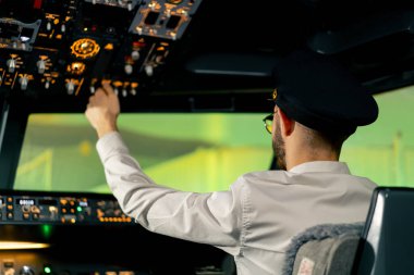 Pilot, yolcu gemisini kalkışa hazırlamak için düğmelere basarak uçağın elektronik aletlerini kontrol ediyor.