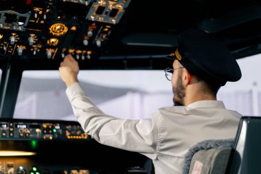 Pilot, yolcu gemisini kalkışa hazırlamak için düğmelere basarak uçağın elektronik aletlerini kontrol ediyor.