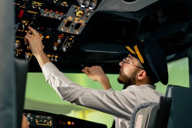 Pilot, yolcu gemisini kalkışa hazırlamak için düğmelere basarak uçağın elektronik aletlerini kontrol ediyor.