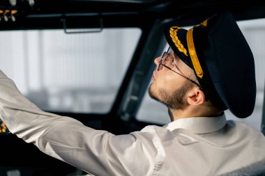 Pilot, yolcu gemisini kalkışa hazırlamak için düğmelere basarak uçağın elektronik aletlerini kontrol ediyor.