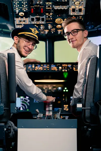 Üniformalı pilotların gülümseyen genç kaptanlarının portresi uçuş simülatörü kokpitinde uçuş hazırlığı yapıyor.