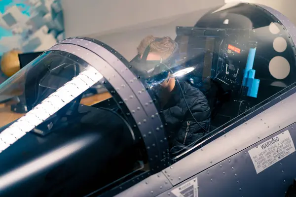 boy sitting in flight simulator military plane wearing virtual reality glasses during flight entertainment
