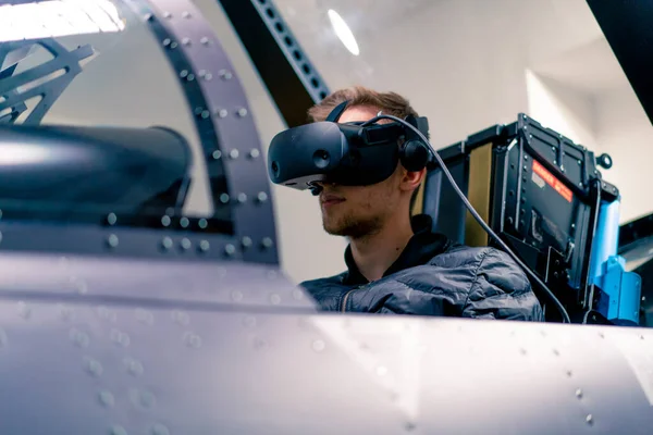 boy sitting in flight simulator military plane wearing virtual reality glasses during flight entertainment