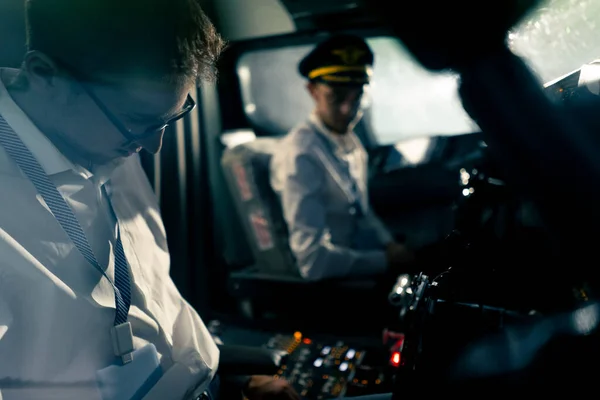 young pilots in the cockpit of the plane control the air transport during the flight the sun shines from window in the far distance simulator