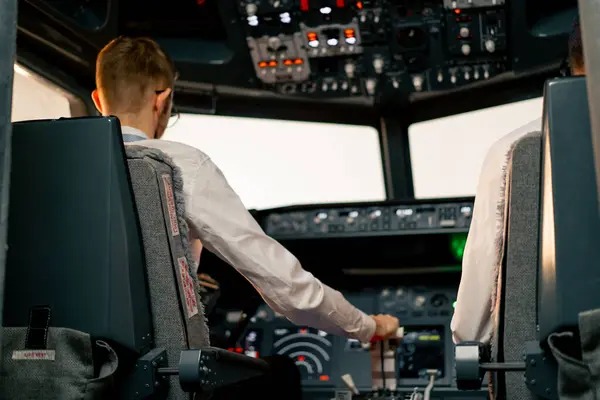 rear view of pilots in the cockpit of an airplane during flight control in turbulence zone flight simulator