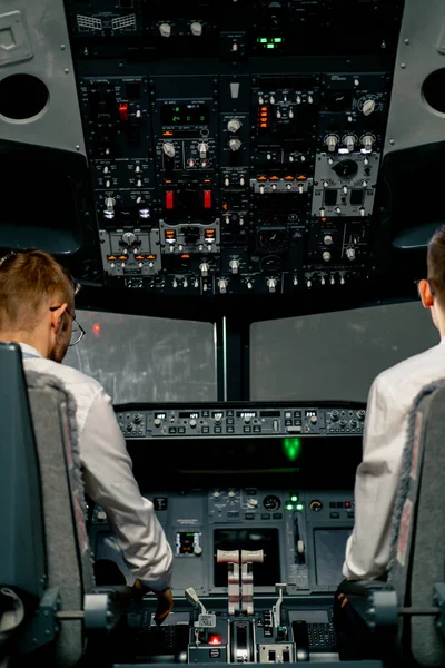 rear view of pilots in the cockpit of an airplane during flight control in turbulence zone flight simulator