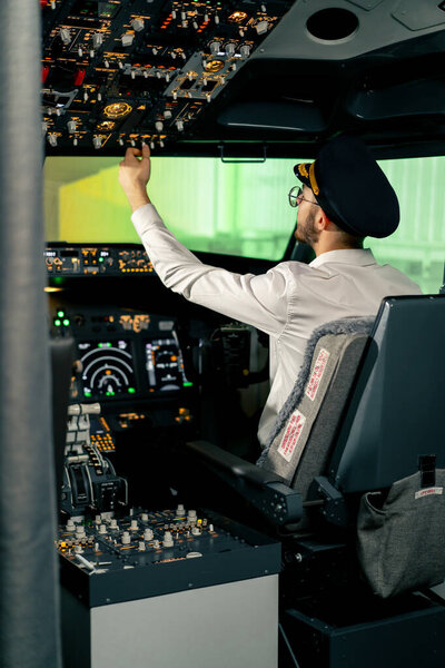 Салон самолета Пилот проверяет электронику самолета, нажимая кнопки Подготовка пассажирского лайнера к взлету