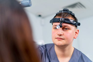 Profesyonel farlı bir KBB doktorunun portresi klinikteki bir hastayı muayene ediyor.