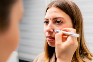 Yakın plan estetik cerrah burun ameliyatı öncesi konsültasyon sırasında hastanın yüzünde izler bırakır.