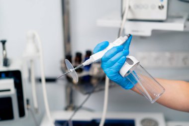 Profesyonel bir endoskopi cihazını klinikteki eldivenli bir elde tutan bir ENT doktorunun yakın çekimi.