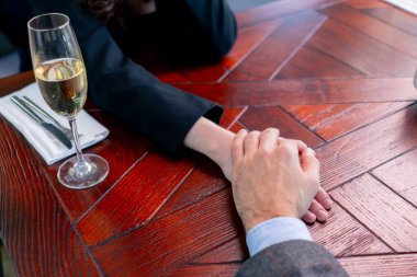 Birbirine aşık bir çiftin restoran konseptinde el ele tutuşması aşk ve destek.