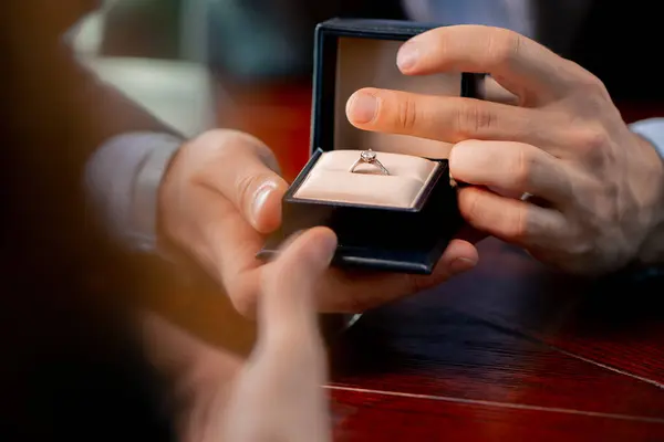 约会特写在一家餐馆里 一个男人向他心爱的人求婚时 拿着一个装有戒指的盒子 — 图库照片