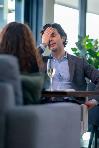 portrait of an upset nervous man sitting in a restaurant with a girl who is quarreling on date conflict