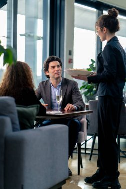 Bir kız garson müşterilere birinci sınıf restoranda konukseverlik ve hizmet sunar.