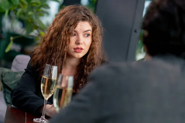 同僚とのビジネスミーティングやメガネのシャンパンを持つ男性とのデートで口論する若い動揺したカーリー女性の肖像画 — ストック写真