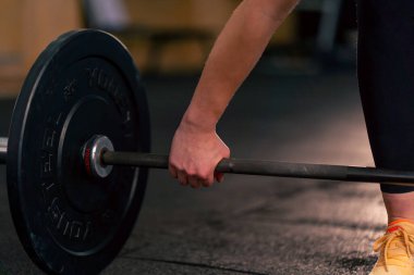 Spor kulübü antrenörlerine yakın plan, spor plakalı bir halteri kaldırmak üzere.