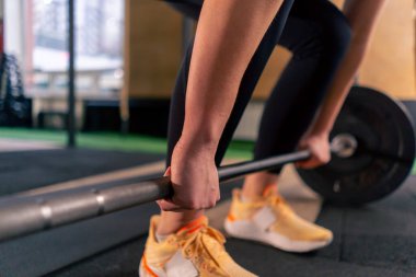 Spor salonunda siyah taytlı bir kız antrenör ağırlığıyla halteri kaldıracak.