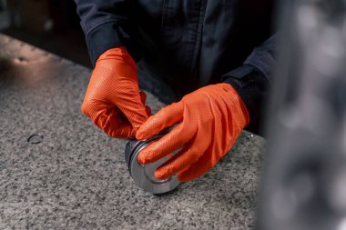 Masadaki bir benzin istasyonunda genç bir motor tamircisi yeni bir piston parçası monte ediyor.