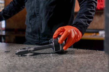 Masadaki bir benzin istasyonunda genç bir motor tamircisi yeni bir piston parçası monte ediyor.