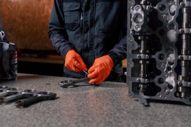 Masadaki bir benzin istasyonunda genç bir motor tamircisi yeni bir piston parçası monte ediyor.