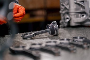 Masadaki bir benzin istasyonunda genç bir motor tamircisi yeni bir piston parçası monte ediyor.