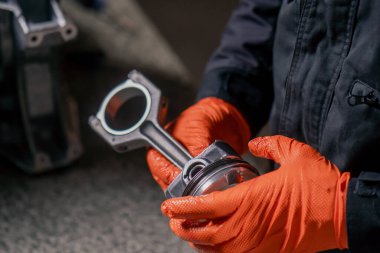 Masadaki bir benzin istasyonunda genç bir motor tamircisi yeni bir piston parçası monte ediyor.