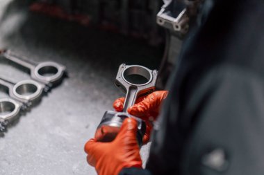 Masadaki bir benzin istasyonunda genç bir motor tamircisi yeni bir piston parçası monte ediyor.