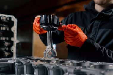 Masanın üstündeki bir benzin istasyonunda genç bir tamirci piston parçası yerleştiriyor.