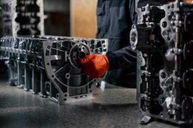 Masanın üstündeki bir benzin istasyonunda genç bir motor tamircisi manuel olarak motordaki krank milini çalıştırır.