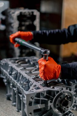 Cıvataları sıkmak için ana bir cihazın elindeki bir benzin istasyonunda motordaki cıvatalarla çalışır.