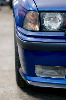 Benzin istasyonuna yakın çekim. BMW 'nin far kısmında koyu mavi renkli siyah tampon yıkanmış.