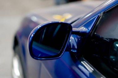 Benzin istasyonunda yakın plan bir BMW yan aynası koyu mavi parlak metali yıkadı