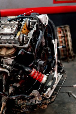 Benzin istasyonunda yedek parça ve onarım için askıya alınmış kirli bir motor var.