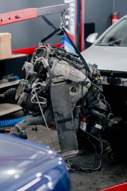 Benzin istasyonunda yedek parça ve onarım için askıya alınmış kirli bir motor var.